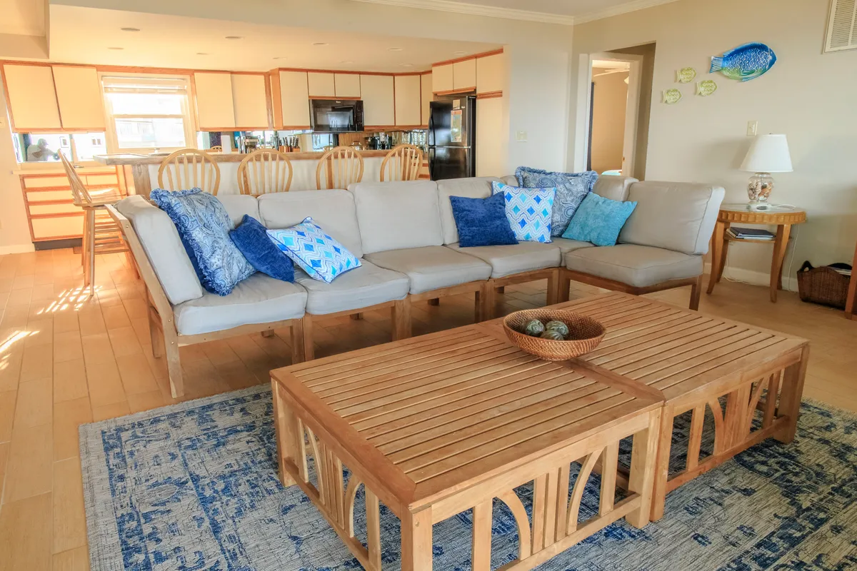 This image features a sofa and coffee table set adjacent to a visible kitchen area, creating an open-concept space perfect for socializing and entertaining guests. The inviting decor and arrangement emphasize both comfort and flexibility, suitable for everyday life or hosting family and friends.